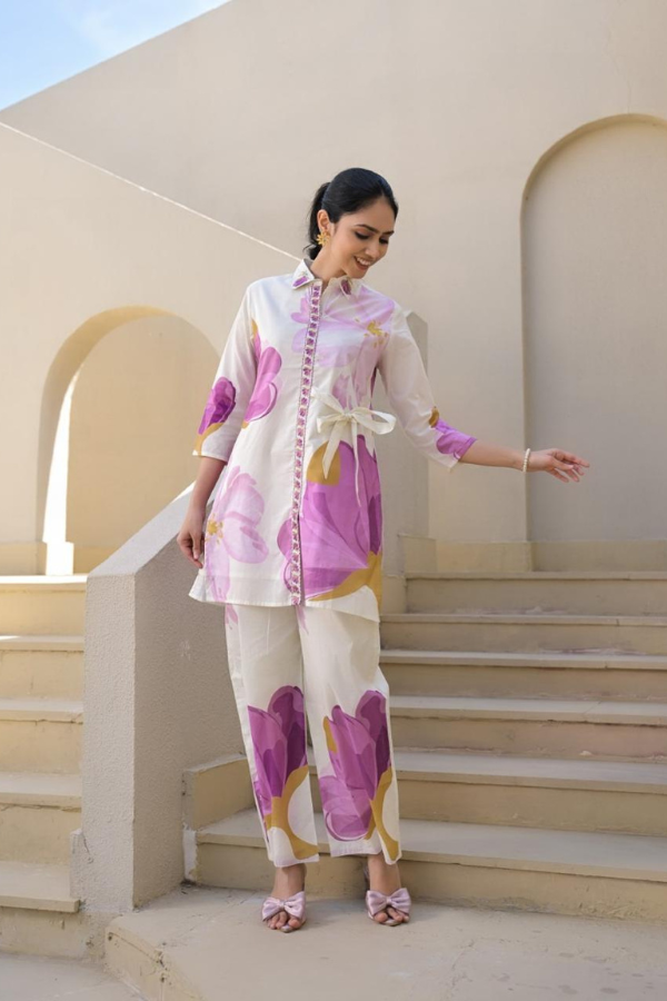 Woman wearing a white and lavender floral print 2-piece co-ord set with a side-tie tunic and straight pants.